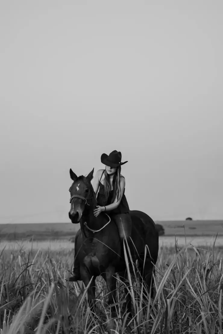 Retrato em preto e branco de amazona a cavalo no pasto alto
