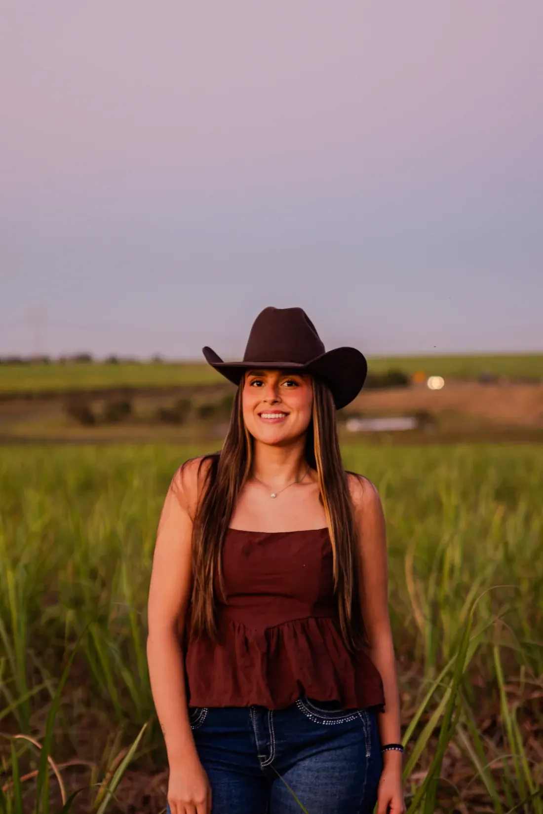 Retrato de amazona de chapéu no canavial durante o entardecer